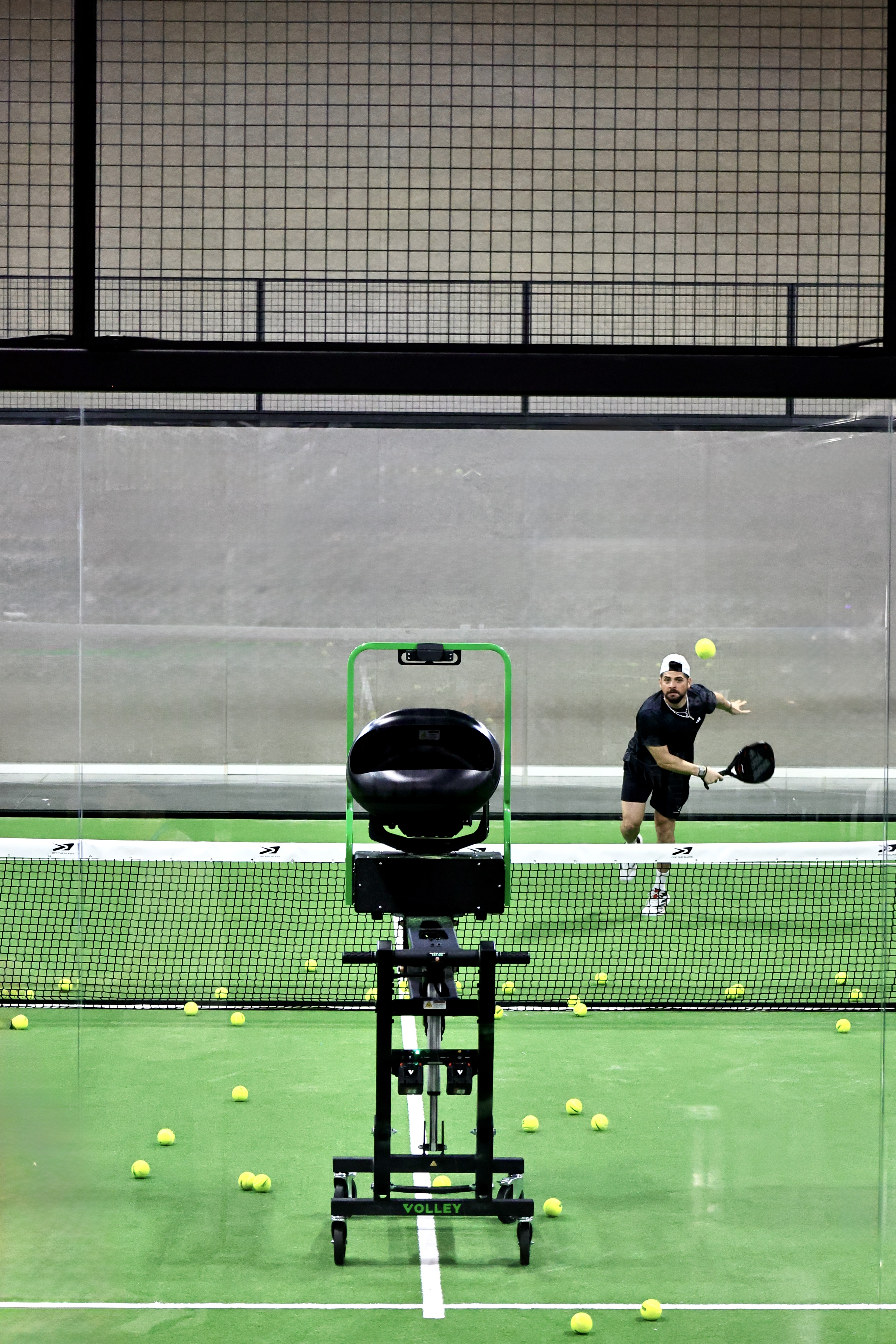 A Volley trainer feeding balls to a player on an otherwise empty court